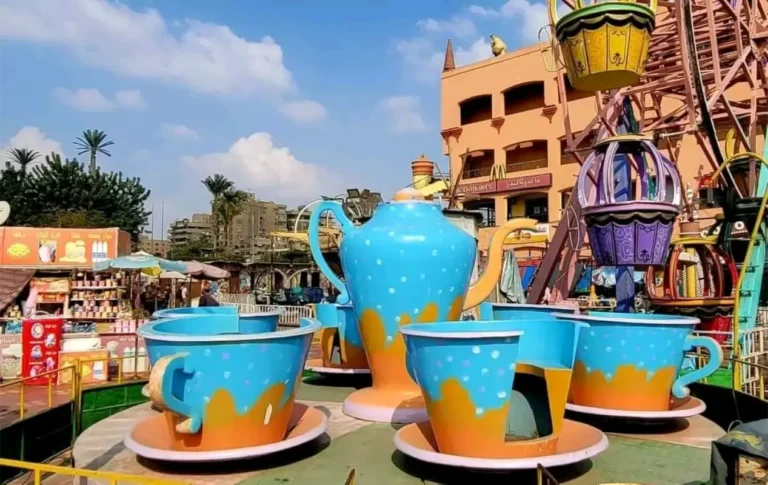 ملاهي ماجيك بارك داخل الحديقة الدولية بمدينة نصر، تضم ألعابًا متنوعة مثل الأرجوحات والسيارات الكهربائية وسط أجواء طبيعية خلابة.