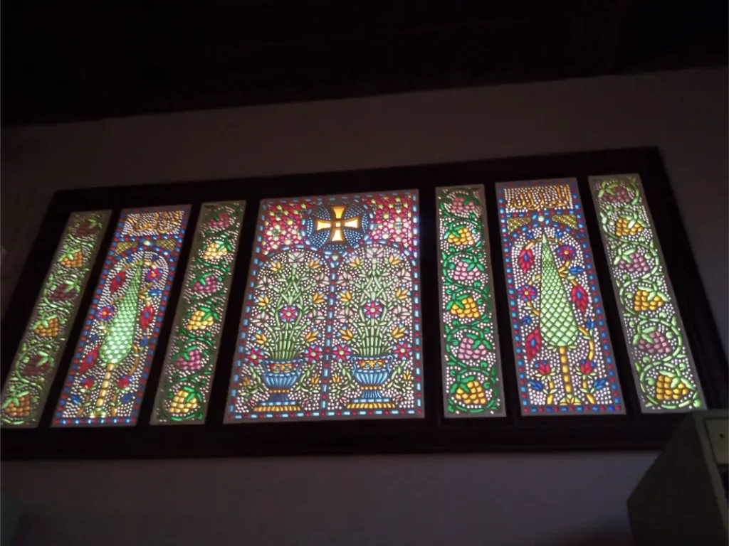 "زجاج معشق ملون داخل المتحف القبطي بالقاهرة، تحفة فنية نادرة تجمع بين الرموز الدينية والزخارف النباتية في لوحة بصرية مبهرة."