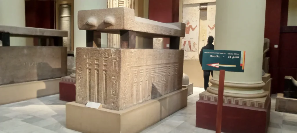 محاكاة مقبرة حسي رع داخل المتحف المصري تُعد من أبرز المعروضات التي تكشف عن فنون العمارة والكتابة في مصر القديمة. يعرض النموذج تابوتًا حجريًا ضخمًا منقوشًا بالنقوش الهيروغليفية والزخارف الرمزية التي تعكس مكانة حسي رع، أحد أوائل الأطباء المسجلين في التاريخ المصري. هذا العرض المتحفي يتيح للزوار فرصة فريدة للتعرف على الطقوس الجنائزية والفن الفرعوني في عصر الدولة القديمة، مما يجعله محطة أساسية لعشاق التاريخ والآثار.